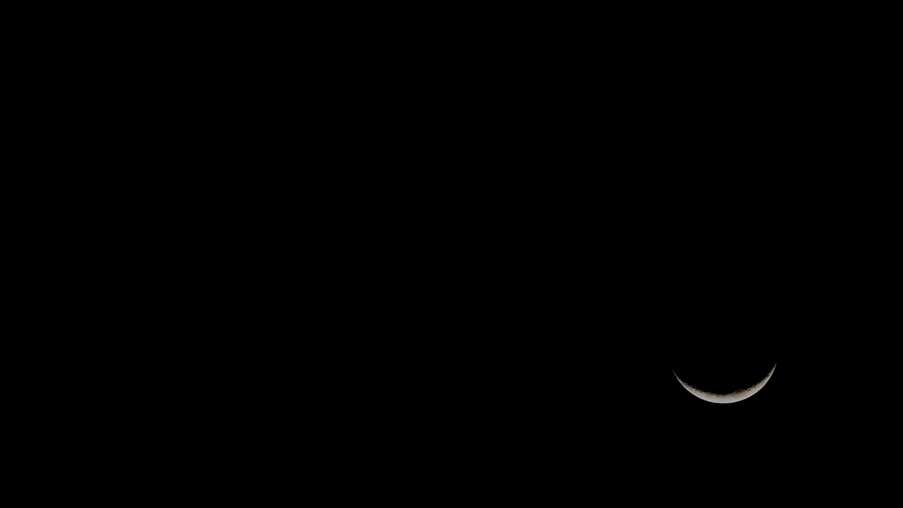 Time lapse of new moon crescent descending in dark black night sky, copy space