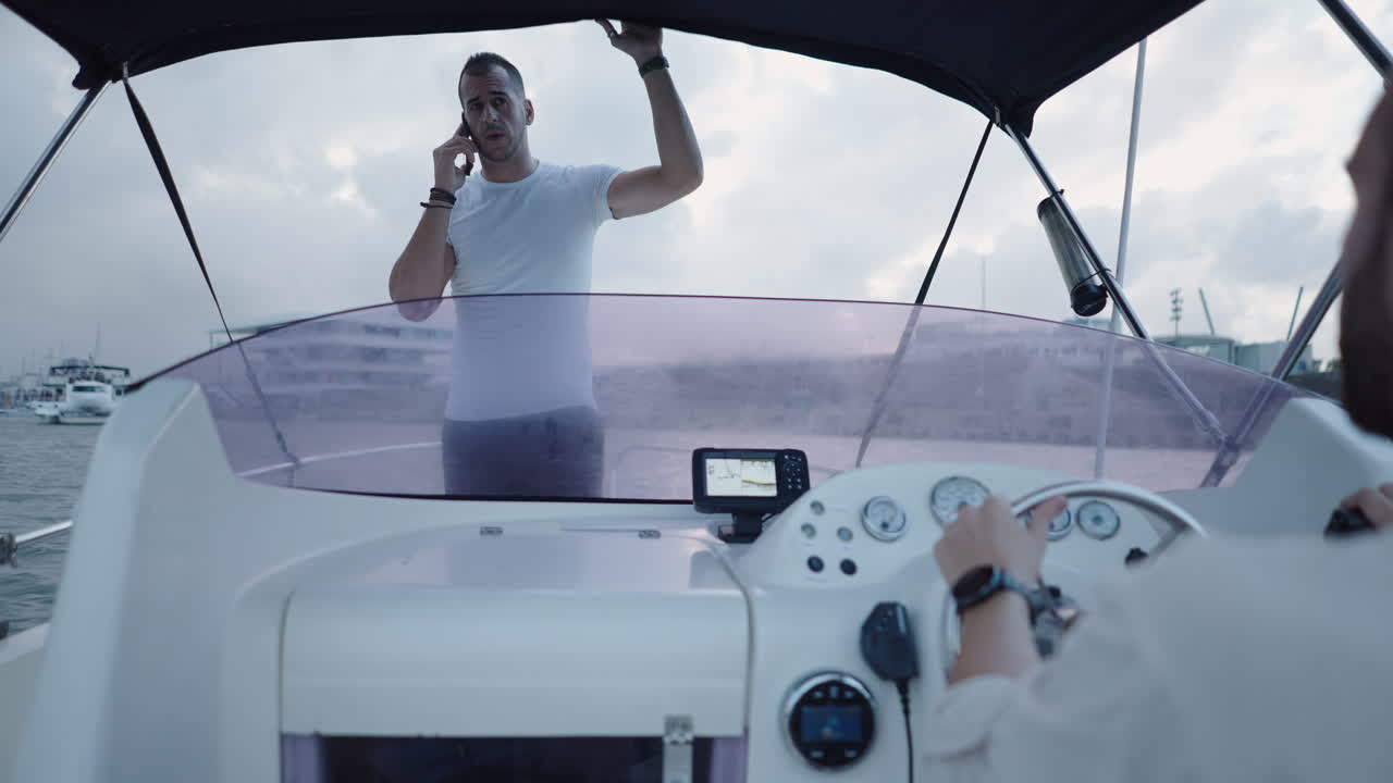 Man on Boat Talking on Phone While Another Person Drives
