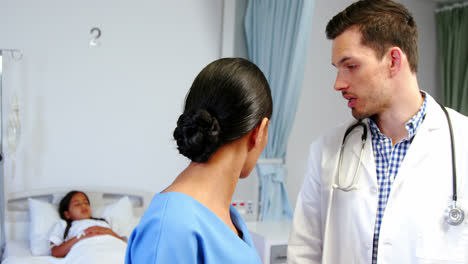 Nurse-and-doctor-discussing-over-clipboard