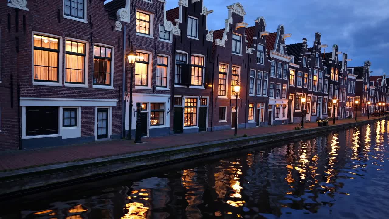 Charming canal-side scene showcasing illuminated brick buildings reflecting in water, capturing the enchanting ambiance of twilight along the waterfront