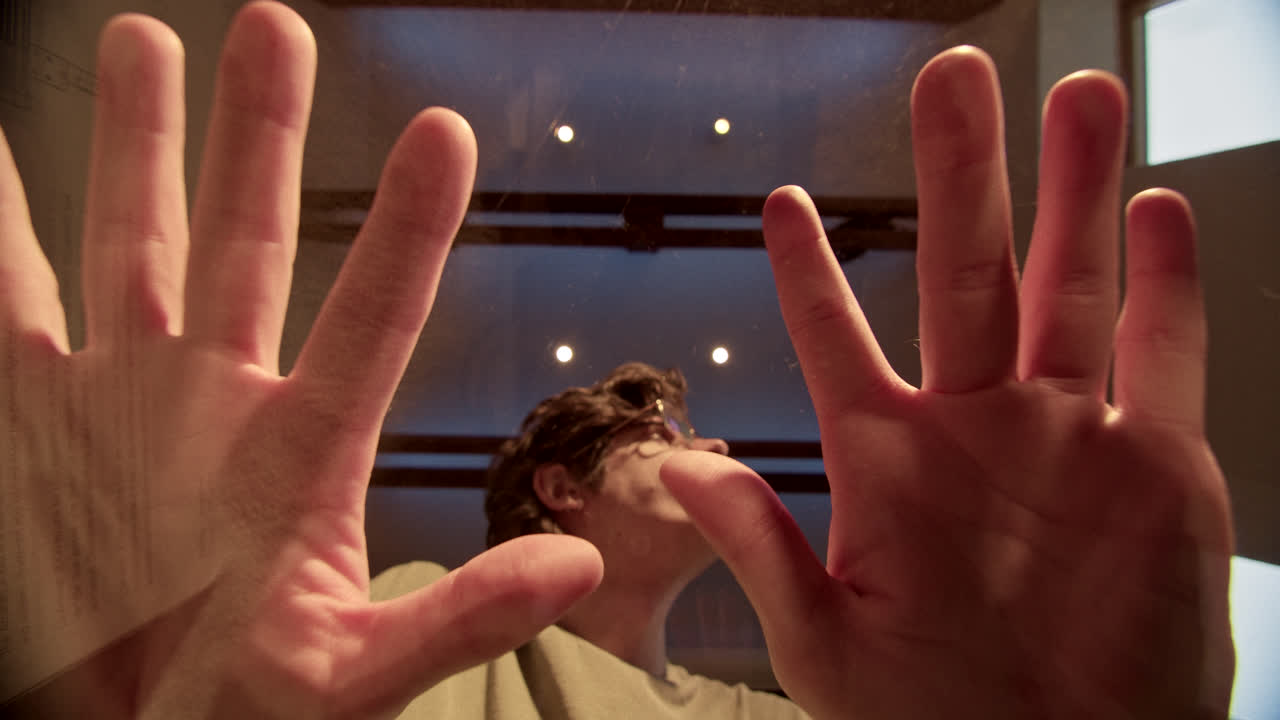 Person looking up through glass with hands pressed against it