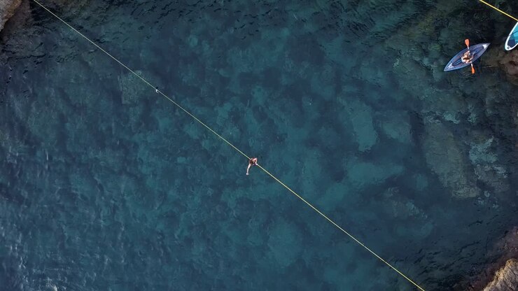 Zenital Zoom In Drone view of a man slackline over the crystal clear waters of Ibiza