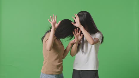 young asian women victims of violence with bruise on bodies making defending gesture and fearing in the green screen background studio