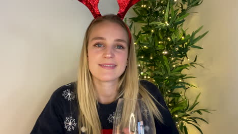 young woman on christmas video call watching someone open a gift and talking to camera