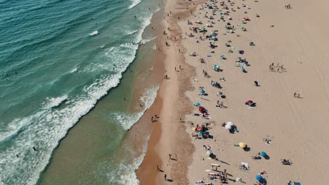 aerial view of a crowded beach with people and umbrellas