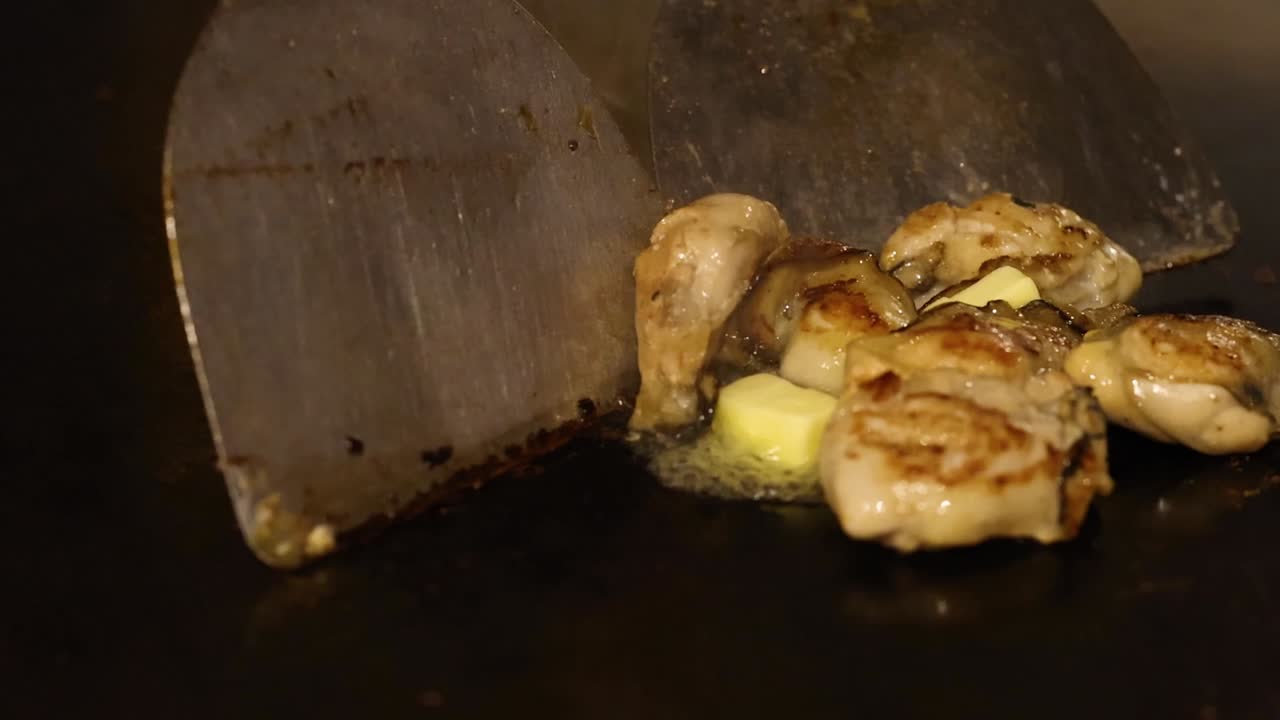 el chef experto hábilmente da vueltas a las ostras en una parrilla.