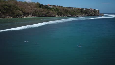 Drone-Shot-circling-around-some-surfers-waiting-for-a-wave-at-Padang-Padang-Beach-in-Bali,-Indonesia