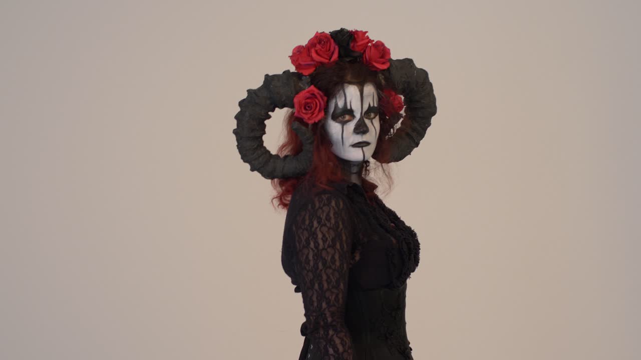 Ragazza in cosplay di Catrina che passa entrando nell'inquadratura da sinistra a destra con uno sfondo chiaro, mezzo primo piano.