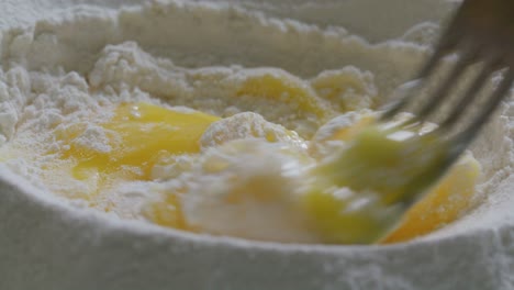 close-up of fork gently mixing egg yolks and flour