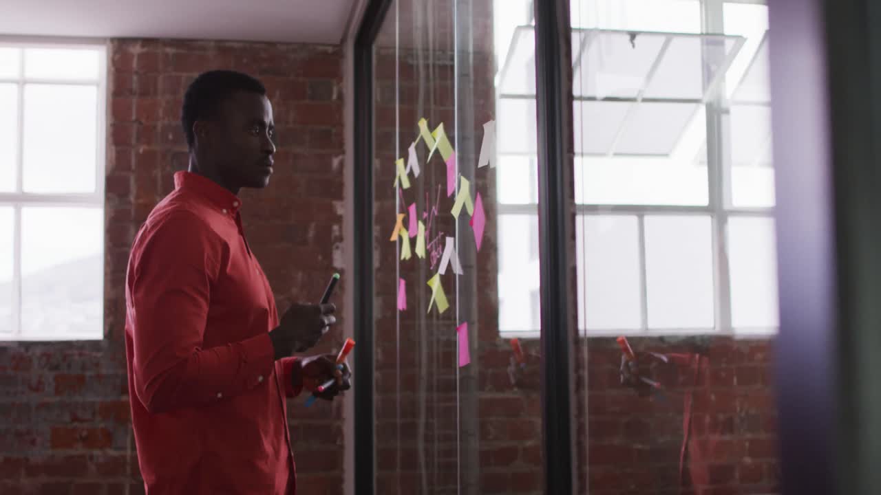 African american businessman standing next to glass wall wondering