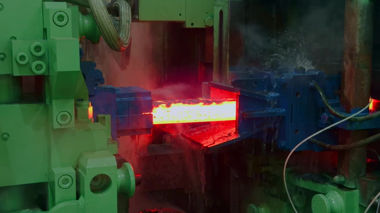 Red hot steel bar passing through heavy mechanical rollers with water cooling in industrial steel mill