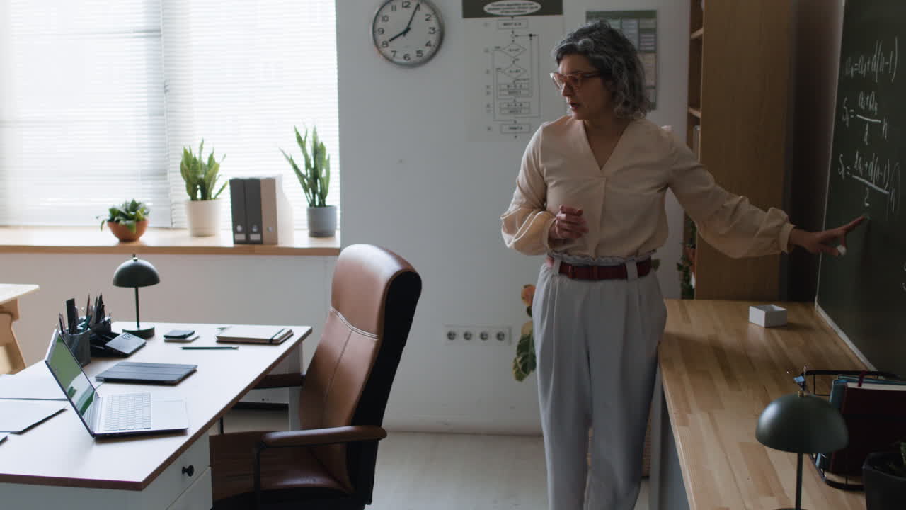 Teacher explaining math on blackboard in classroom