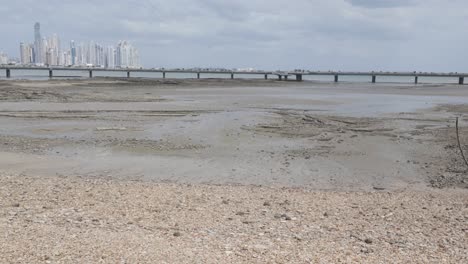 panama city's casco viejo waterfront during low tide with distant bridge and cloudy sky