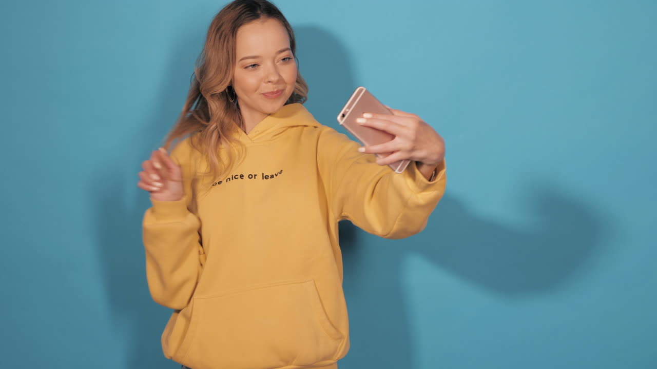 노란색 후디를 입고 셀피를 찍는 젊은 여성