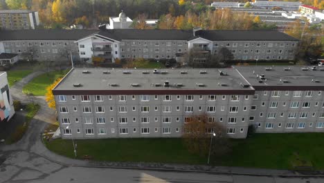 aerial view of a flat residential building complex in a city neighborhood with autumn colored trees around, crane wide shot