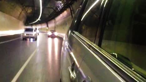 Rear-view-mirror-footage-of-vehicles-driving-through-a-tunnel