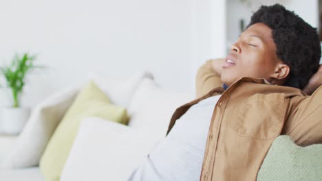 feliz hombre afroamericano descansando y relajándose, sentado en el sofá