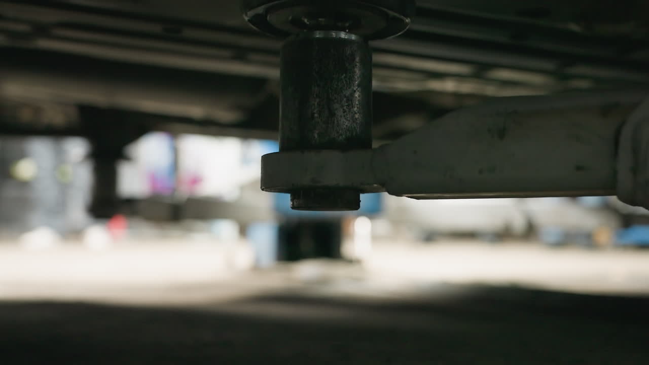 primer plano del ascensor de automóvil debajo del vehículo que muestra un sutil movimiento hacia arriba, con detalles borrosos en el fondo que mejoran la profundidad de la configuración del garaje