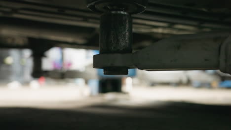 primer plano del ascensor de automóvil debajo del vehículo que muestra un sutil movimiento hacia arriba, con detalles borrosos en el fondo que mejoran la profundidad de la configuración del garaje