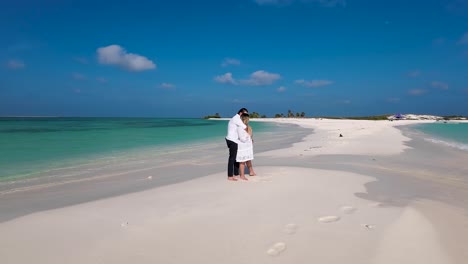 couple hugging watching sea on lonely white sand beach, romantic honeymoon travel