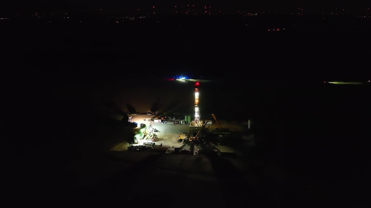 una estación de perforación de petróleo por la noche con el departamento de bomberos en funcionamiento - disparo de panorámica aérea