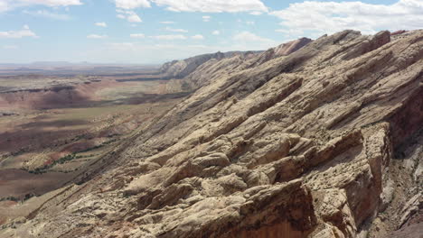 Drone-captures-breathtaking-panorama-of-rugged-cliffs-and-vast-landscape-under-a-sky-dotted-with-fluffy-white-clouds