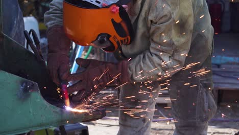 man working as blacksmith wearing a security mask and welding with blow torch - slowmotion