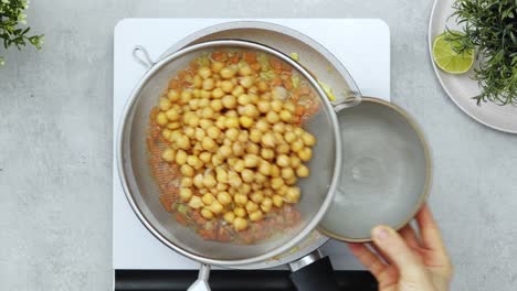 Anonymous-person-adding-chickpea-water-into-vegetables