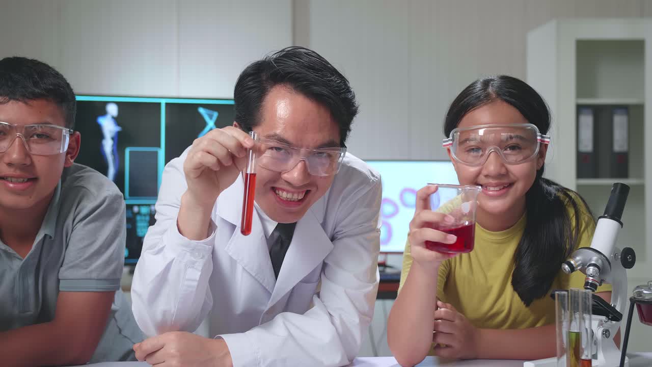 Young Asian Boy, Girl And Teacher Smiling While Holding Test Tubes In Classroom. Study With Scientific Equipment