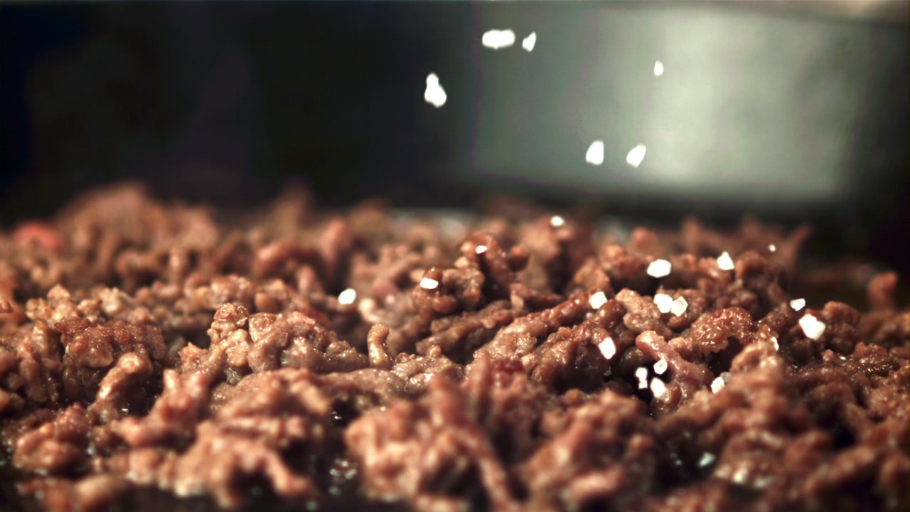 Slow Motion Close-Up of Salt Falling on Cooking Ground Meat