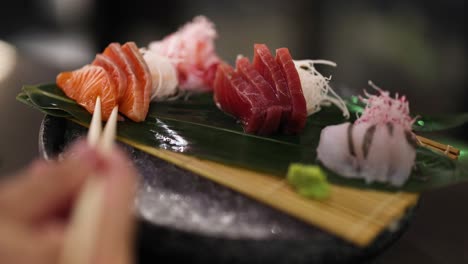 chopsticks picking up sushi from a platter