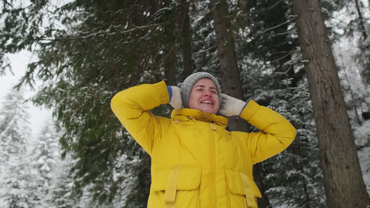 Woman enjoying snowfall in a winter forest