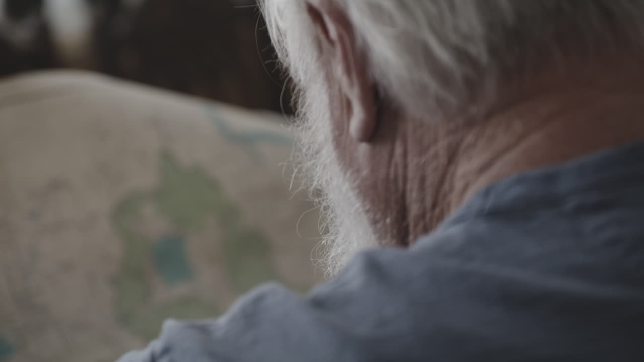 앉아서 종이 지도를 들고 있는 노인의 뒷모습