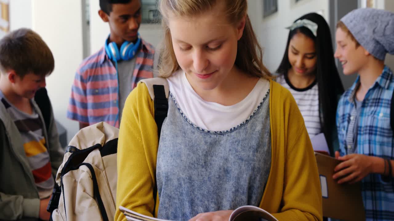 Portrait of smiling schoolgirl standing with notebook in corridor