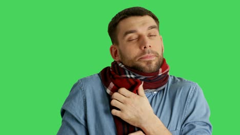 mid closeup shot of a sick man in scarf caughing and sneezing. background is green screen.