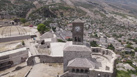 aerial arc around clock tower of historic gjirokaster castle atop hillside