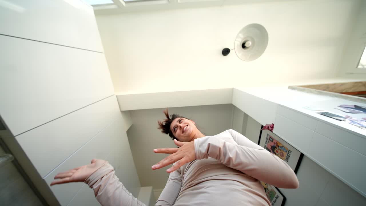 Giovane donna energica che balla e gesticola in una cucina moderna