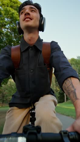 man cycling in park with headphones