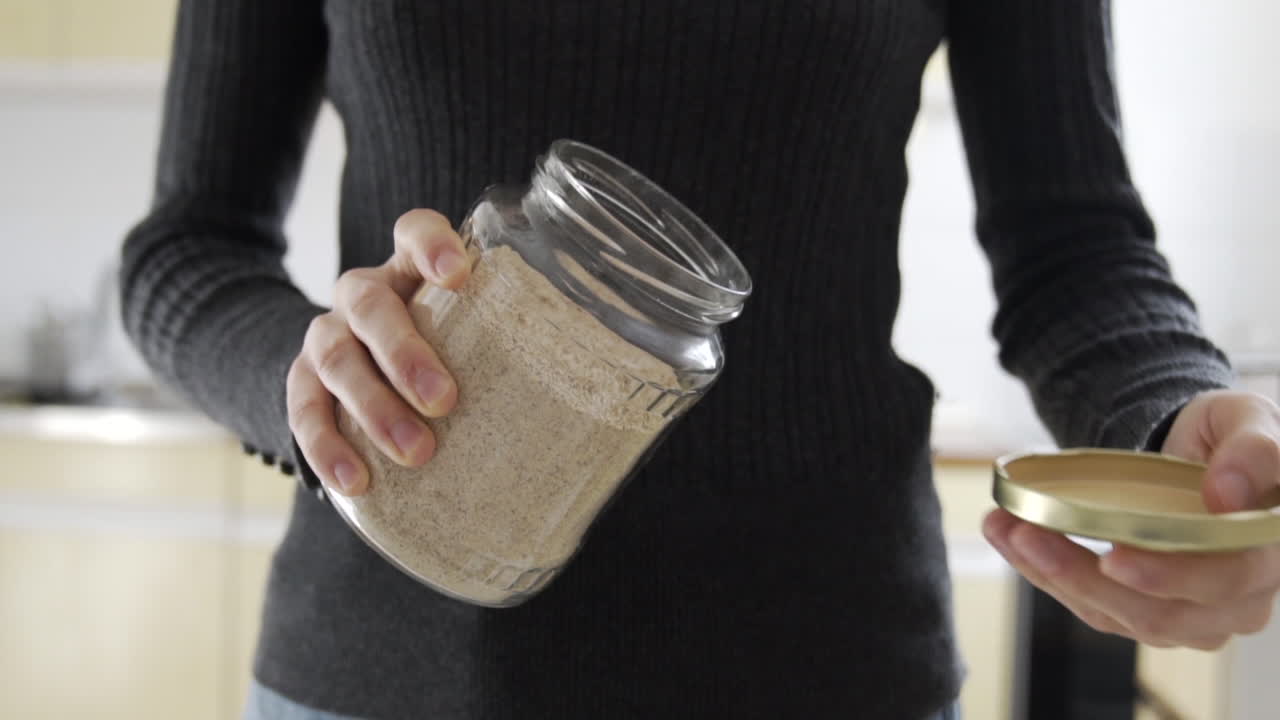 글루텐이 없는 갈색 밀로 가득 찬 병을 여는 중간 샷