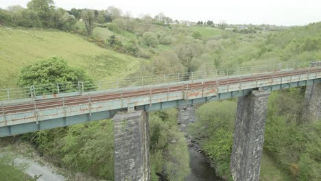 Antena-Hacia-El-Antiguo-Puente-Ferroviario-Sobre-Un-Exuberante-Valle-En-El-Condado-De-Kerry,-Irlanda