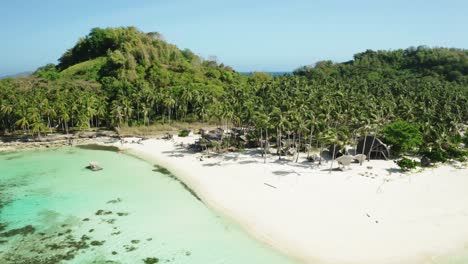 Tropical-island-with-beachfront-bungalows,-white-sand,-palm-trees-and-turquoise-water