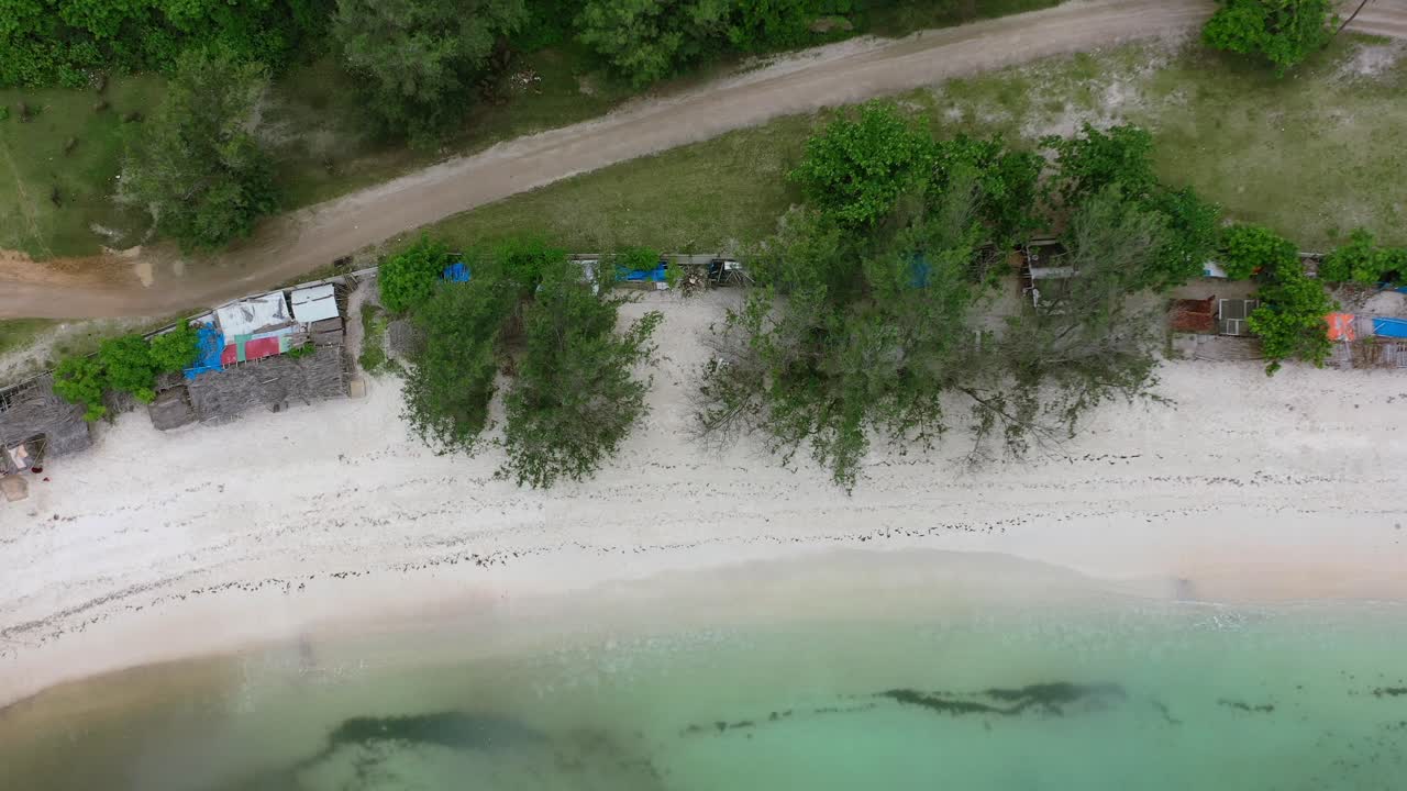 인도네시아의 열대 청록색 물이 있는 하얀 모래 해변 해안선을 따라 있는 비포장 도로