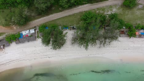 Camino-De-Tierra-A-Lo-Largo-De-La-Costa-De-La-Playa-De-Arena-Blanca-Con-Agua-Turquesa-Tropical-En-Indonesia,-Arriba-Hacia-Abajo