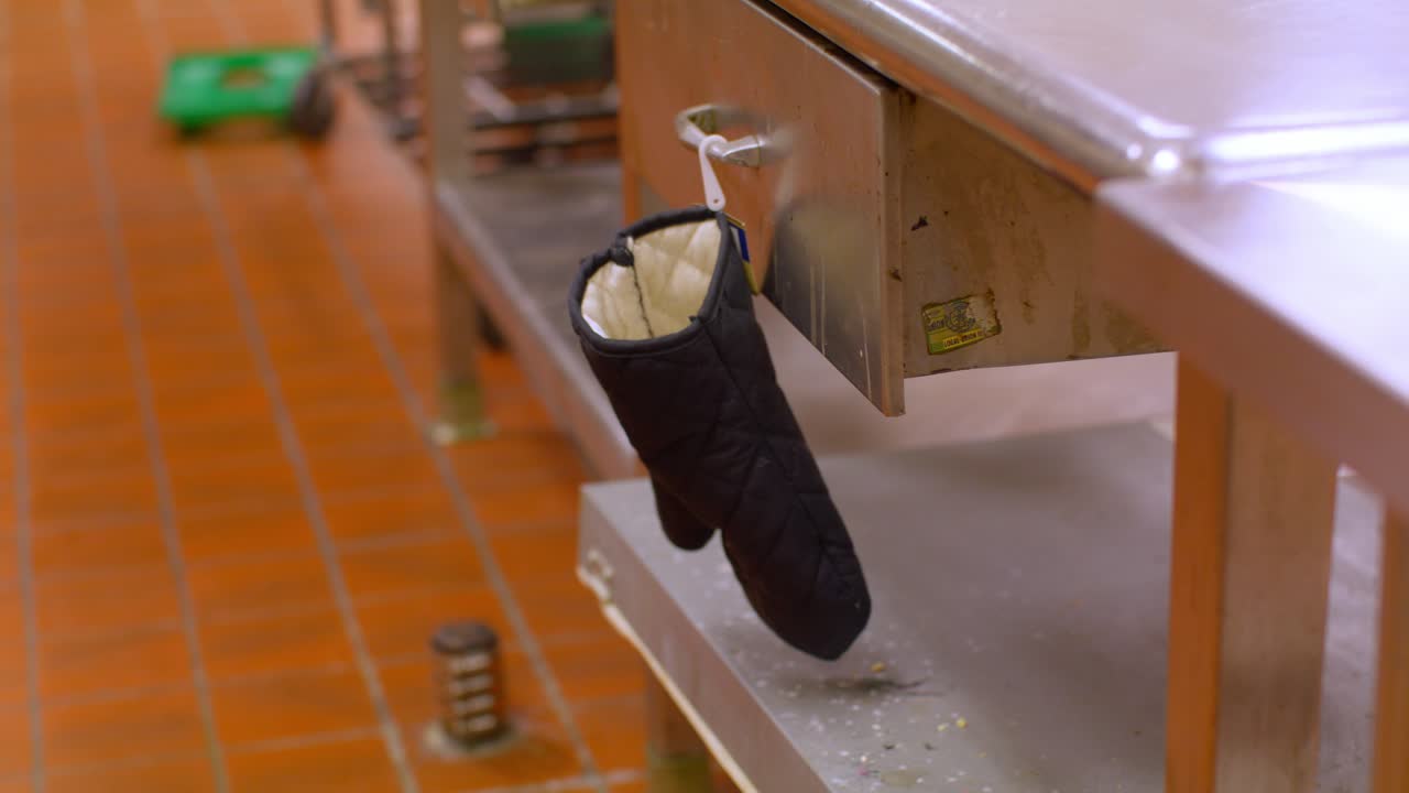 Oven mitt on a hook in a commercial kitchen with stable video shot.