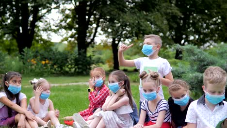 grupo de niños alegres que aprenden al aire libre en la escuela después del bloqueo de cuarentena grupo de niños alegre que aprenden al aire libre en el colegio después del cerramiento del cuarenteno