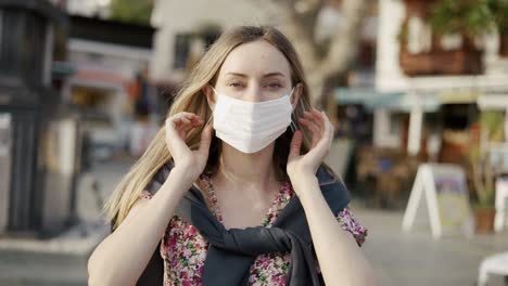 blonde woman putting on medical mask on crowdy street