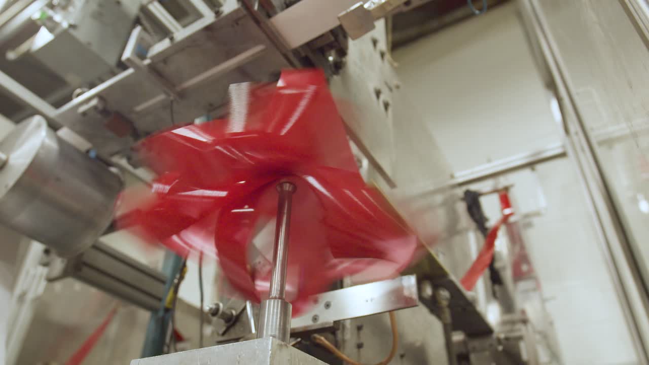 A ribbon bow–making machine looping ribbon around itself multiple times to form a decorative gift bow used for present wrapping