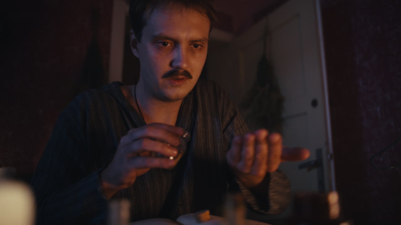 Man Pouring Contents from a Bottle in a Dimly Lit Room