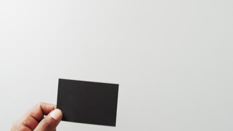 hand of biracial man with black business card on white background, copy space, slow motion