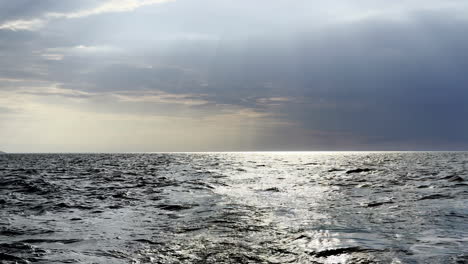 rays of sunlight pierce through a stormy sky over the north sea, creating a dramatic contrast of light and shadow turbulent water break in the clouds